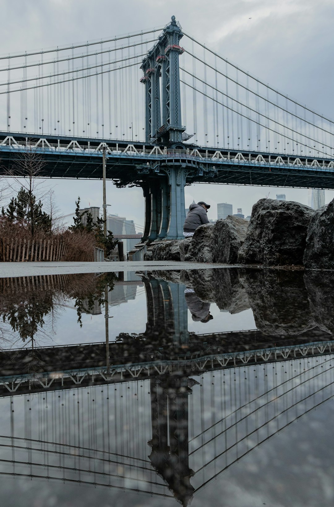 man in blue jacket standing on gray concrete bridge during daytime