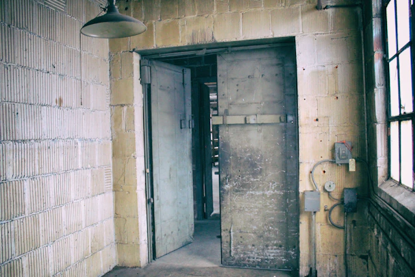 An industrial-style metal door slightly ajar, revealing a bright workspace inside.