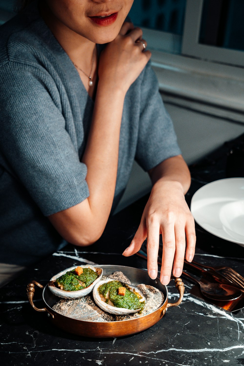 person in gray shirt holding white ceramic plate with food