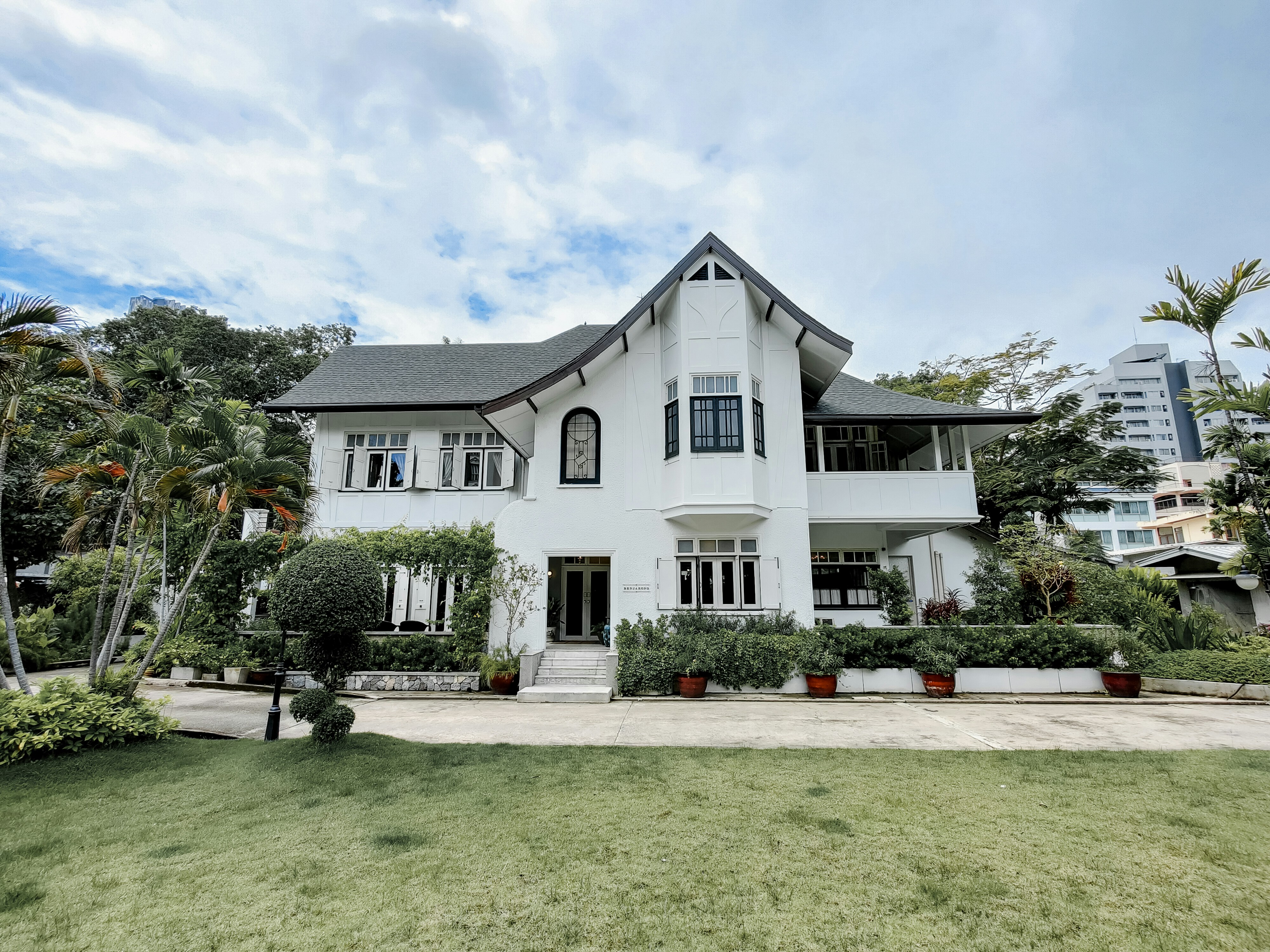white and gray concrete house near green grass field under white clouds during daytime