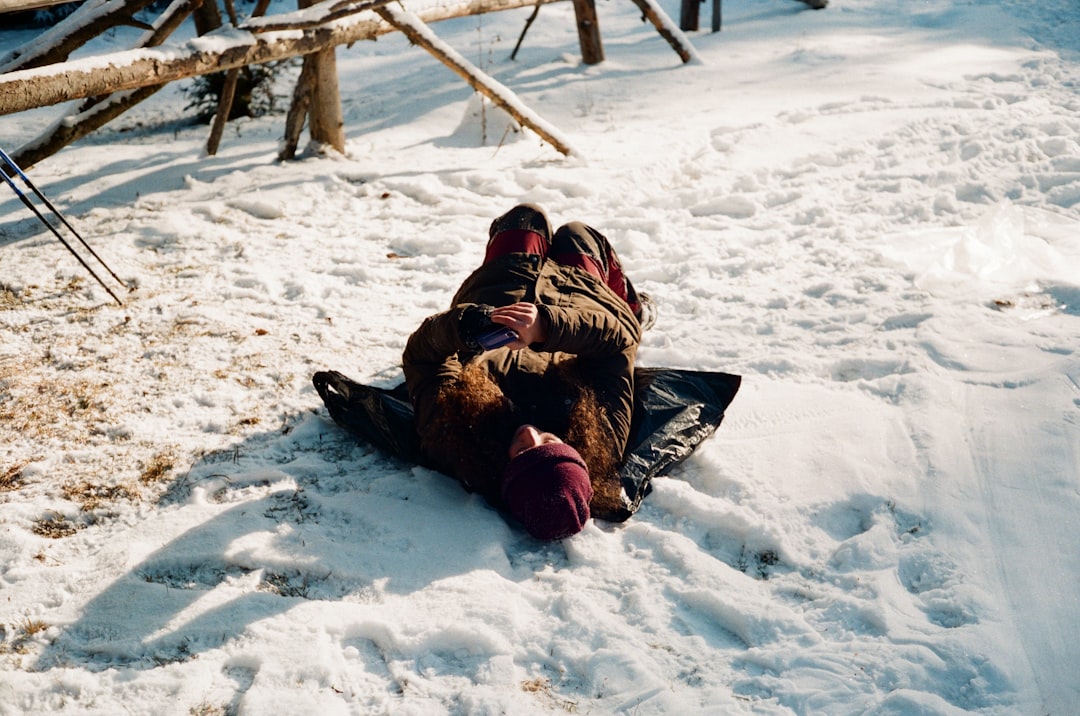 person lying on snow covered ground during daytime