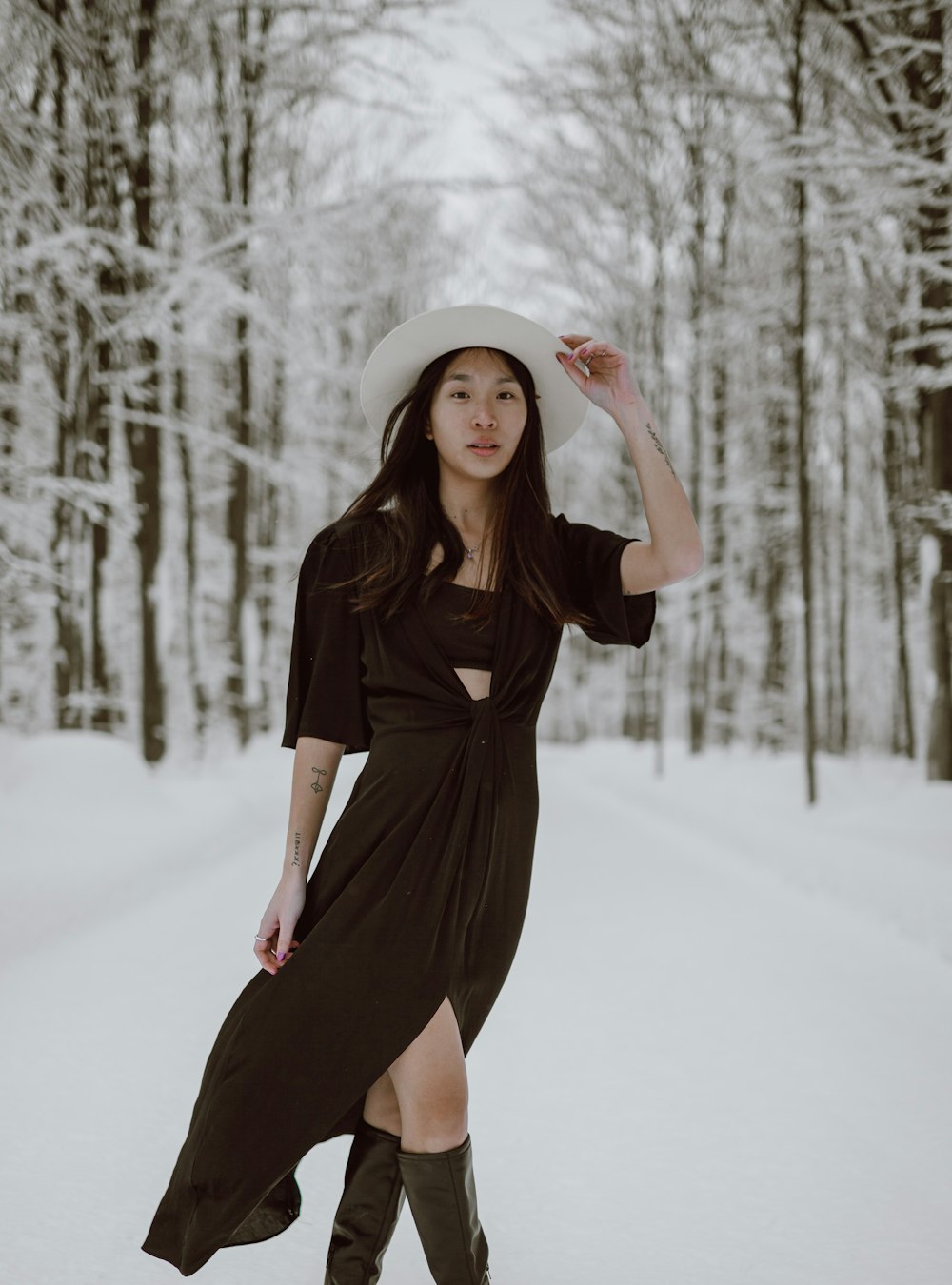 mulher no vestido preto de manga comprida em pé no chão coberto de neve durante o dia