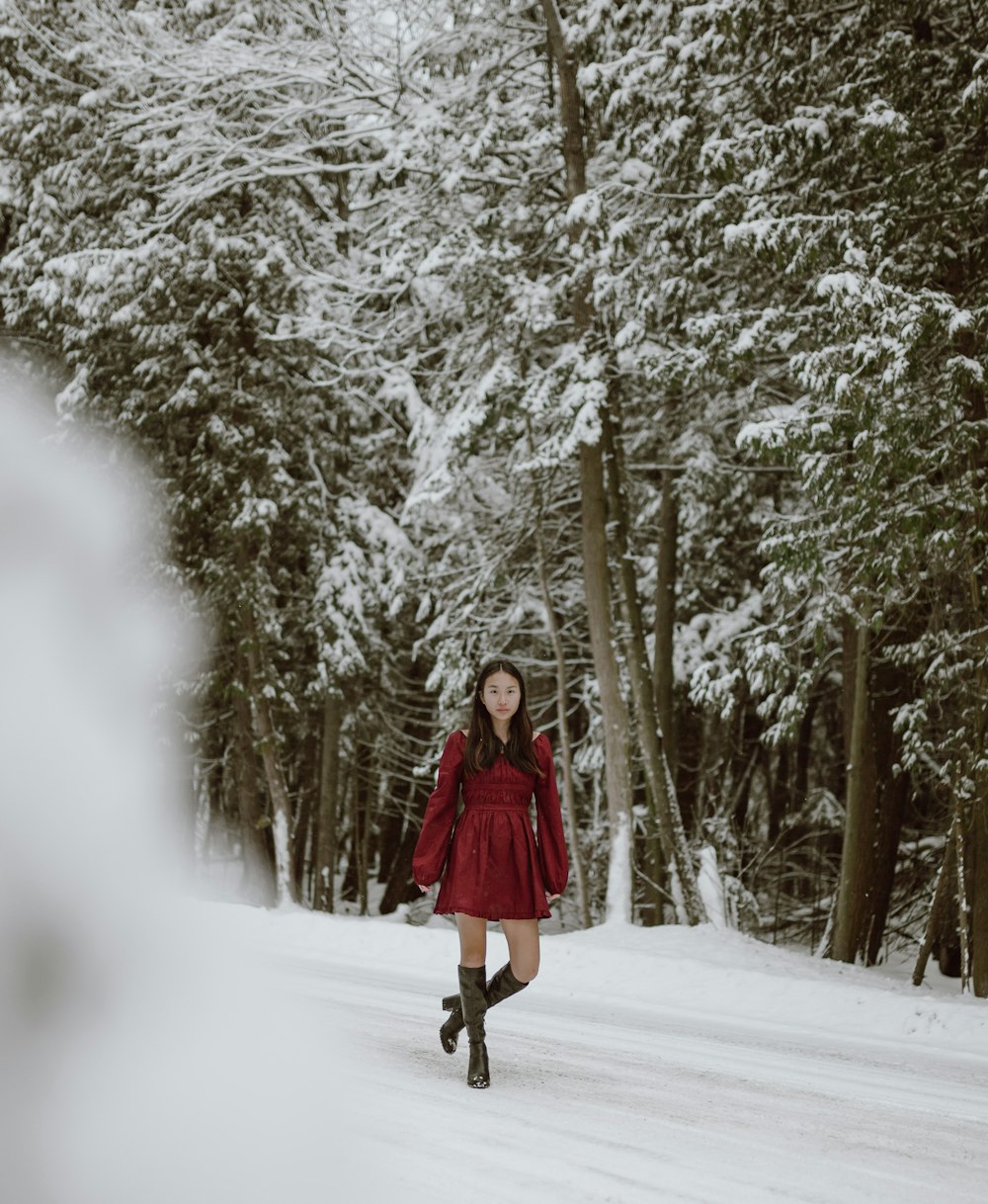 woman in red coat standing on snow covered ground