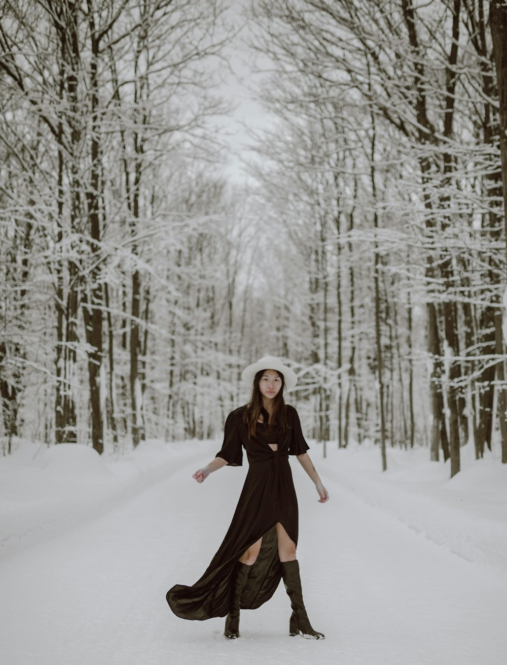 mulher no casaco preto em pé no chão coberto de neve durante o dia