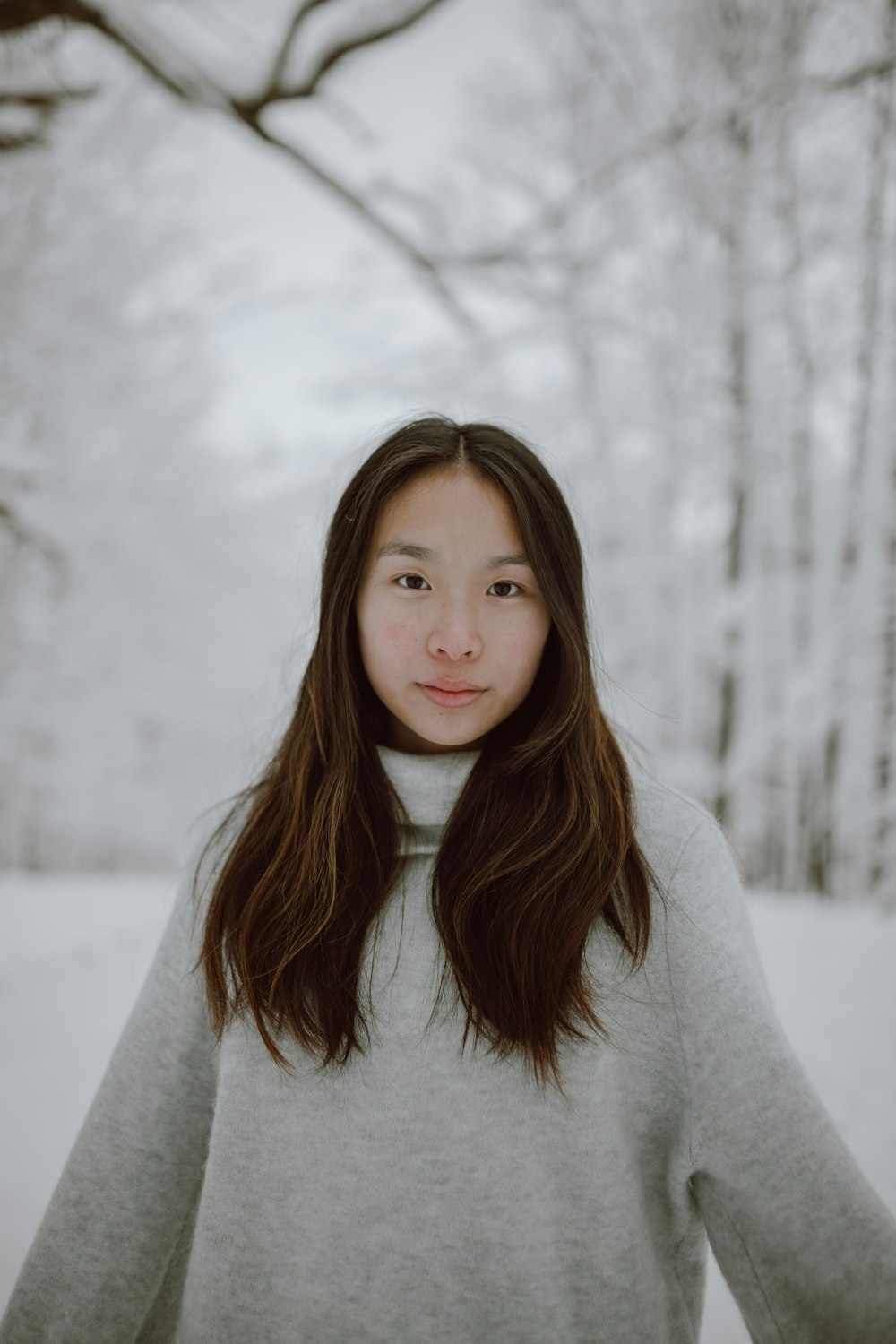 woman in white sweater standing on snow covered ground during daytime