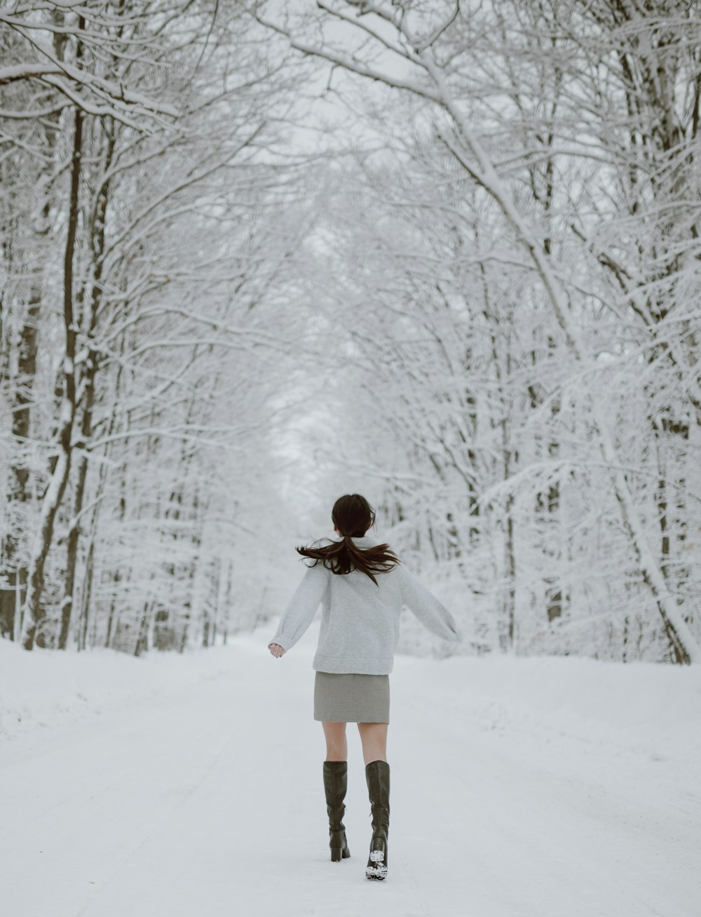 woman in white coat standing on snow covered ground