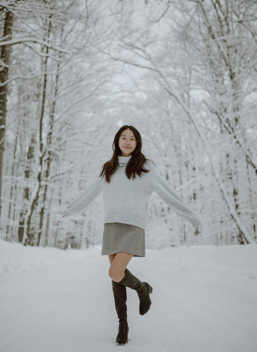 昼間、雪に覆われた地面に立つ白い長袖シャツを着た女性