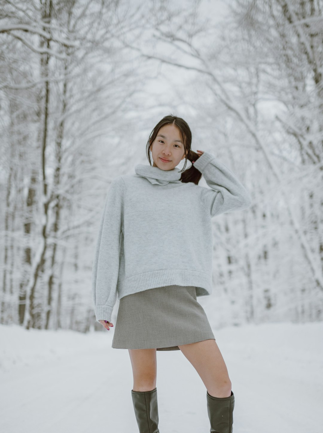 woman in white sweater standing on snow covered ground during daytime