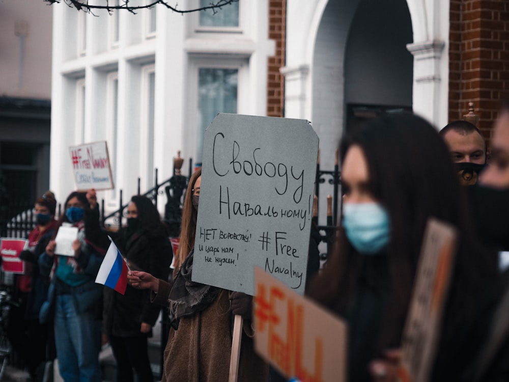 woman in black jacket holding white and black signage