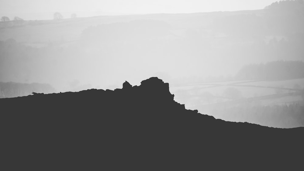 grayscale photo of mountain under cloudy sky