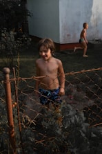 Realistic children playing outdoors in a sunny garden with colorful toys around.