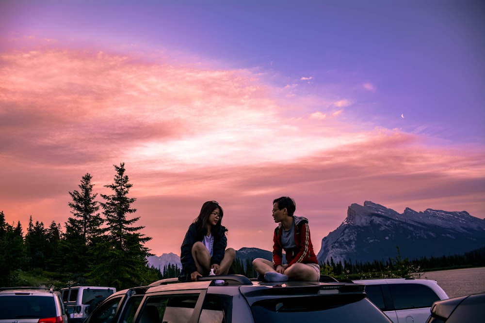 couple sitting on car hood during sunset