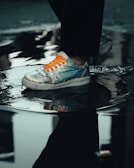 person in black pants wearing gray and orange nike sneakers
