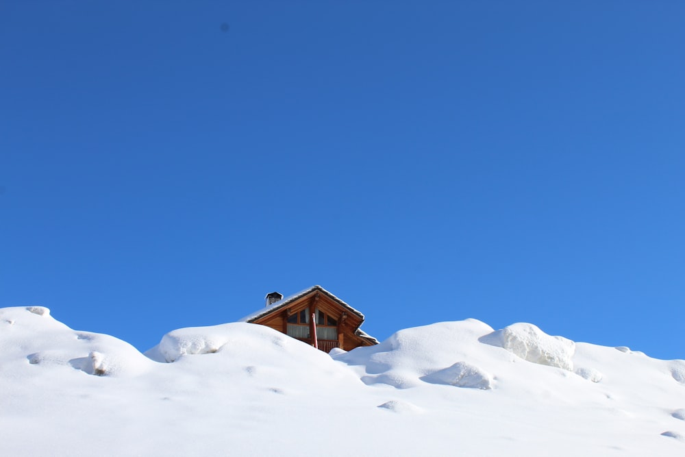 brown wooden house on snow covered ground under blue sky during daytime