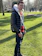 Smiling woman wearing a sleek reverd jacket standing in a sunlit urban park.