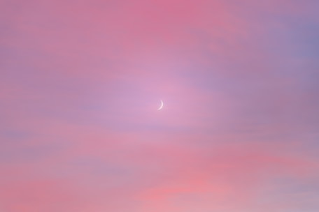 A dreamy blue starry background with soft violet and pink brushstrokes surrounding a glowing yellow moon.
