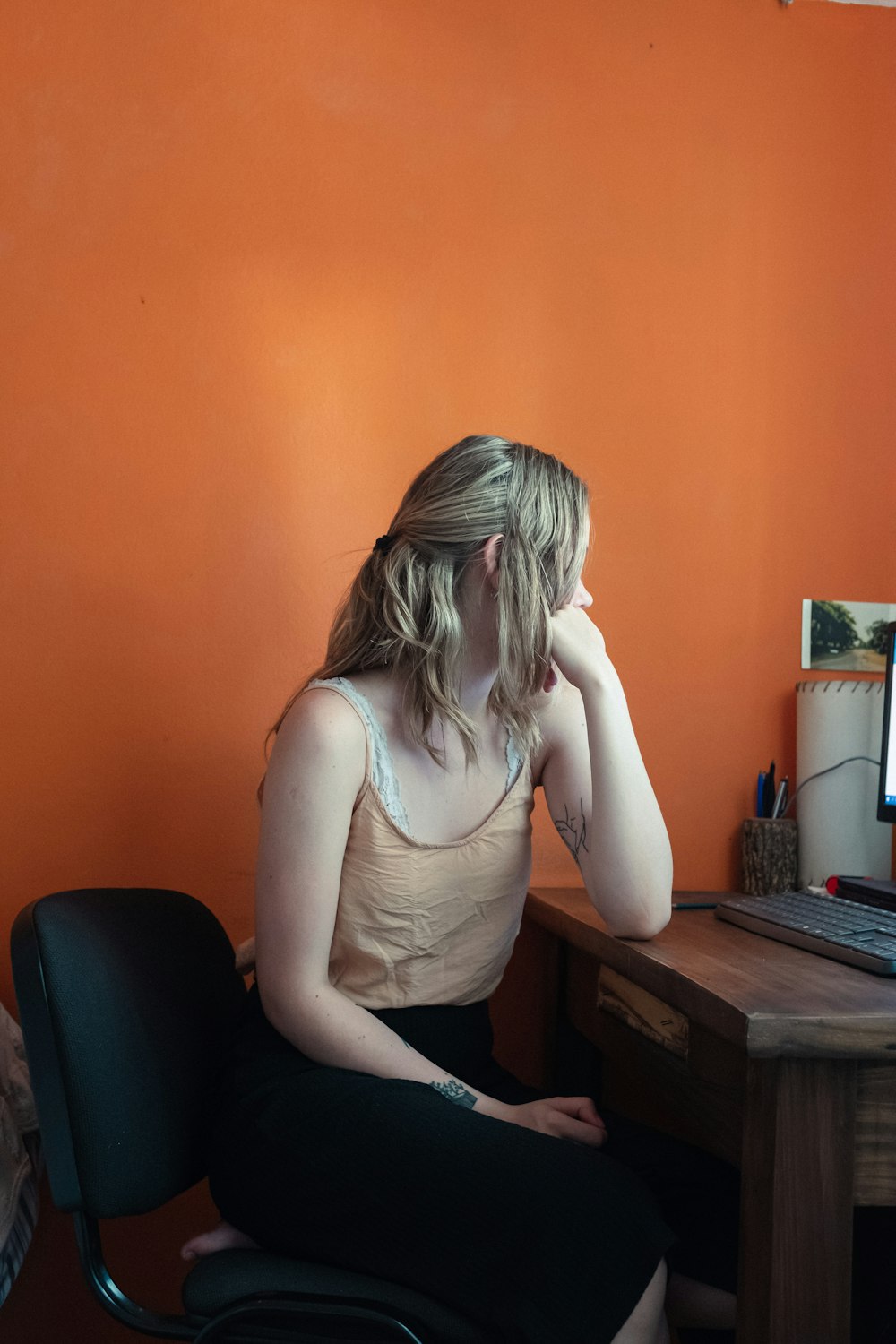 woman in white tank top sitting on black office rolling chair