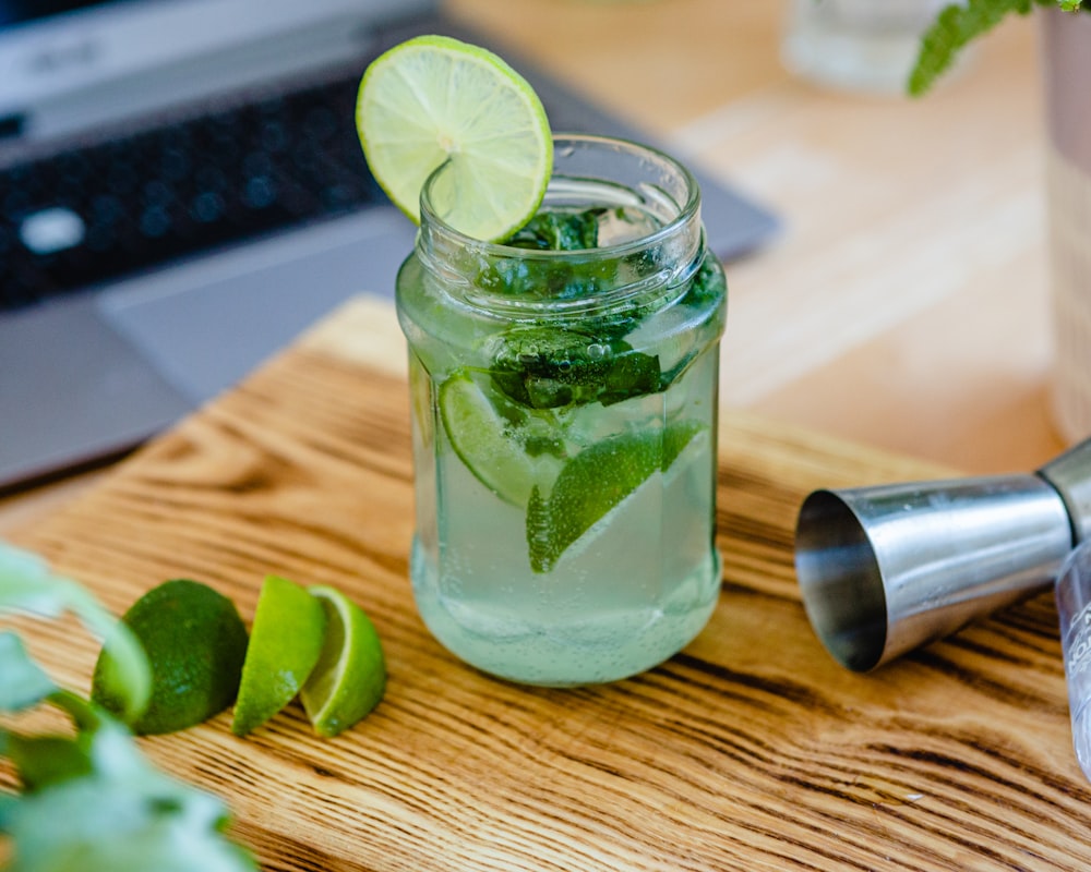 Tasse en verre transparent avec un liquide vert et des tranches de citron