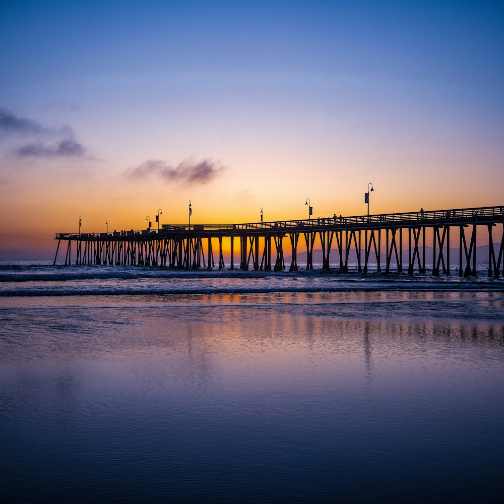 brown wooden dock on sea during sunset