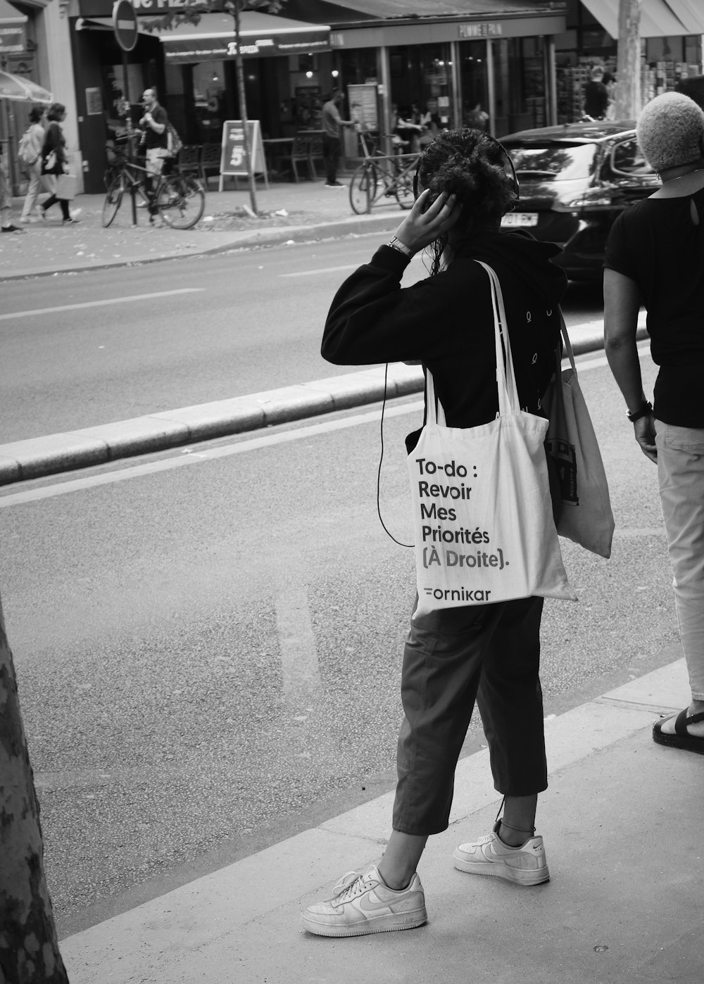 woman in black jacket and pants standing on sidewalk