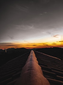 A wide shot showing a team member inspecting a newly finished roof at sunset.