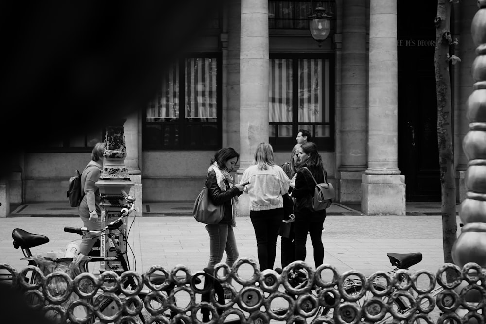 Foto in scala di grigi di donna e uomo in piedi vicino all'edificio