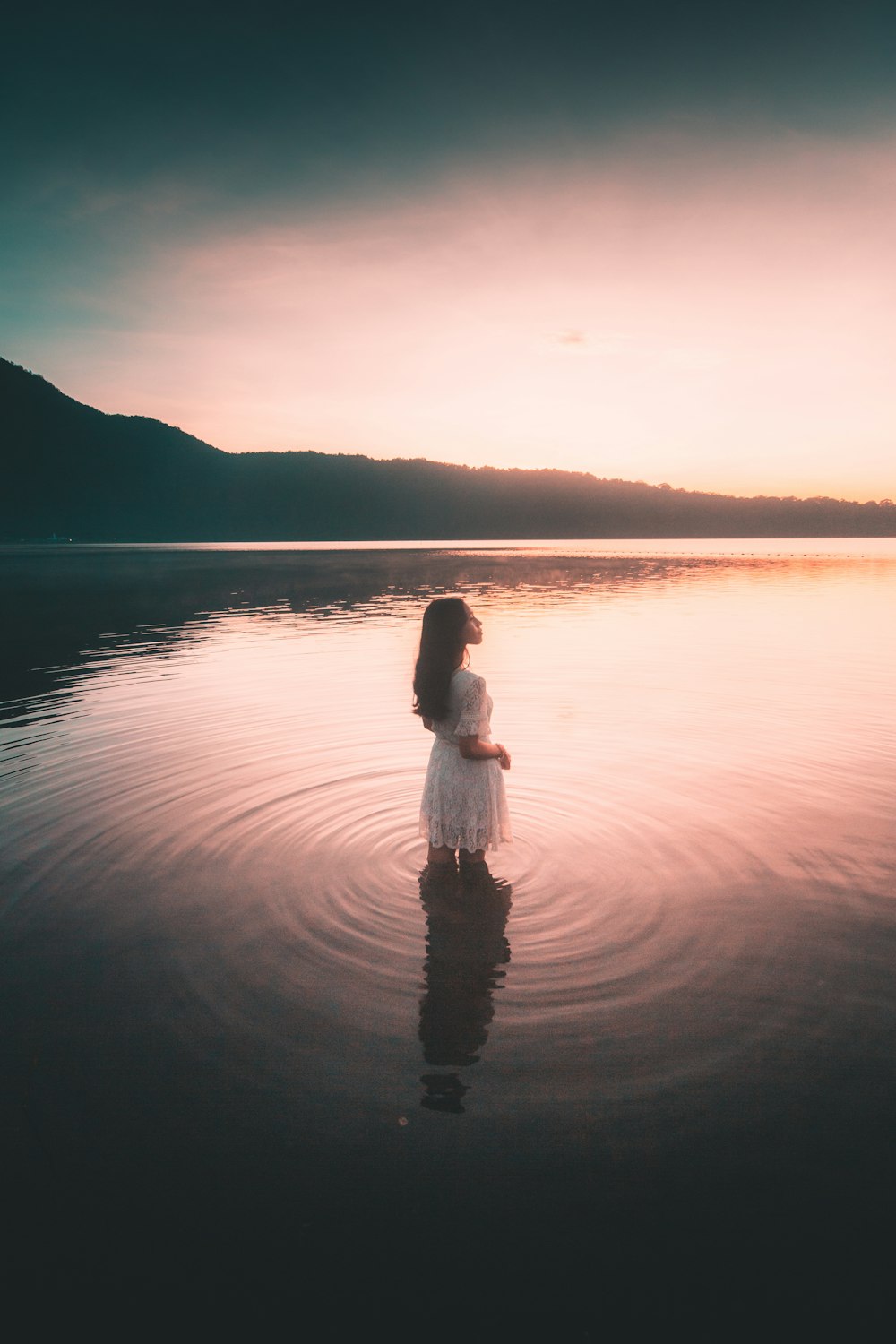 Mujer en vestido blanco de pie sobre el agua durante el día