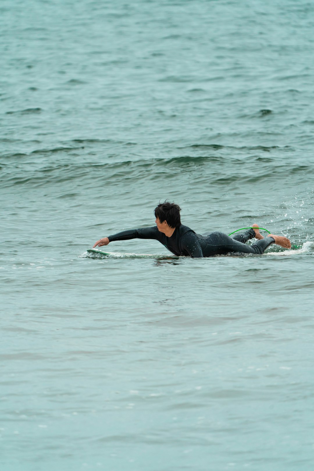 woman in black wetsuit lying on water