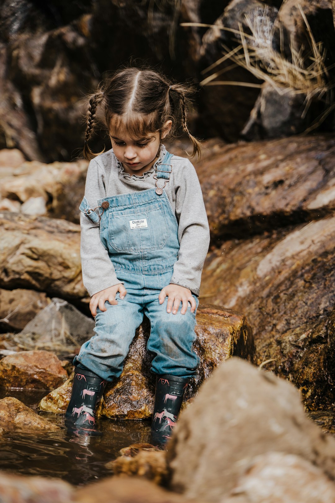 girl in blue denim jacket and blue denim jeans sitting on brown log during daytime