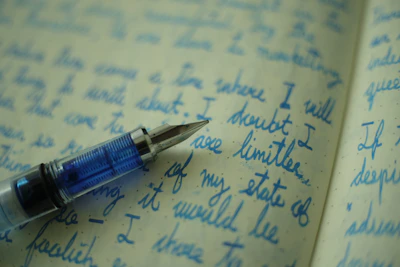 A close-up of handwritten poetry pages with a fountain pen lying across them.