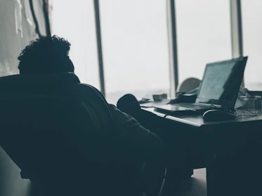 A person relaxing at their desk with the XXL heating pad wrapped around their shoulders.