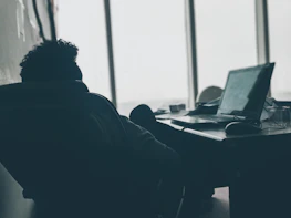 A candid shot of the CEO working at their desk with a laptop and notes.