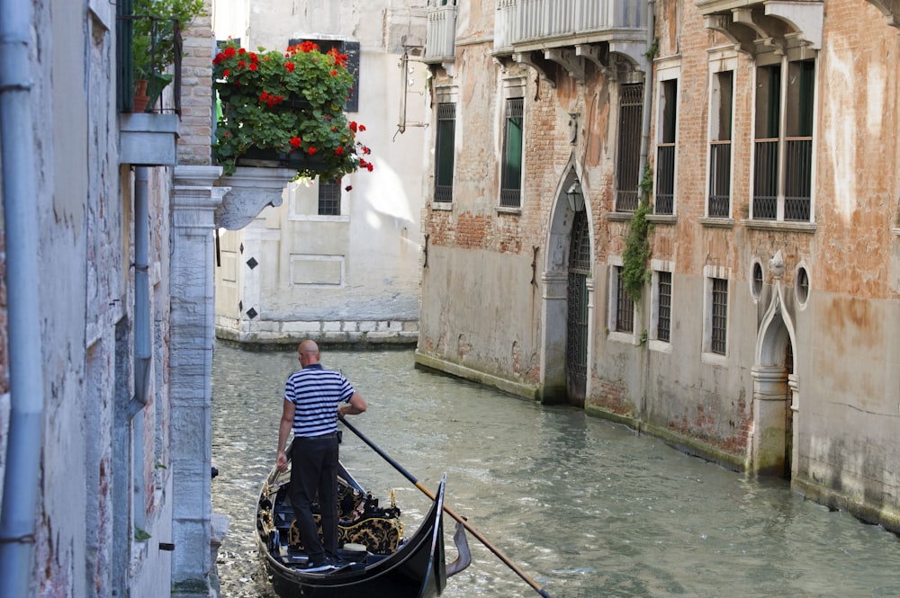 man in blue and white striped long sleeve shirt riding on black boat on river during