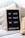 A cozy setting featuring a letter board with a wooden frame, displaying inspirational messages: 'BE KIND', 'BE CALM', 'BE SAFE', and '#SPREADJOY'. It is placed on a soft, textured surface alongside textured pillows, including one with a yellow and white polka dot pattern.
