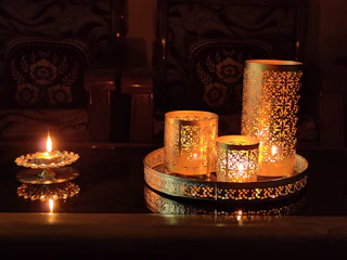 A selection of sensual massage oils and candles glowing warmly on a bedside table.