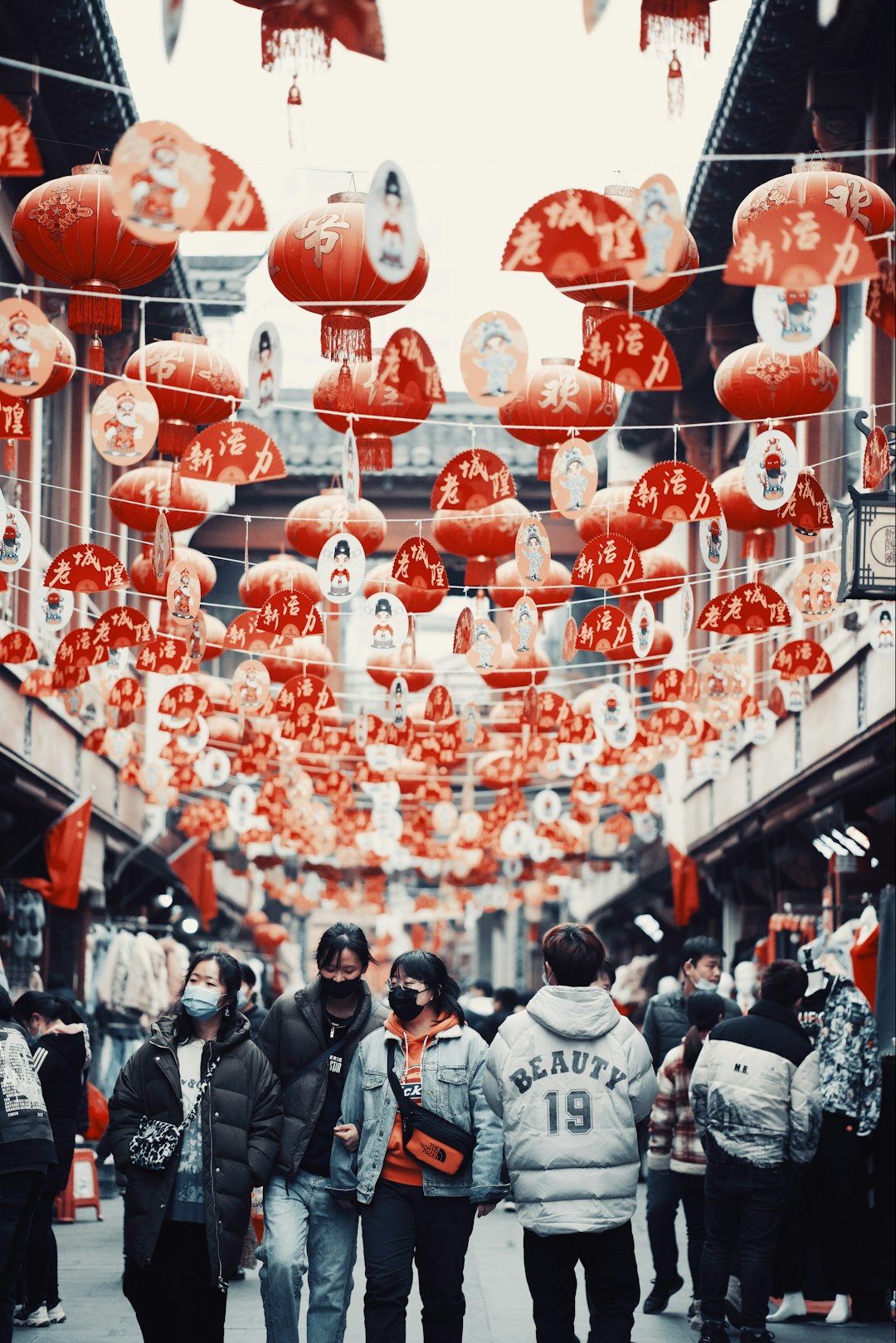 people in black and white shirts standing on red and white hanging lanterns