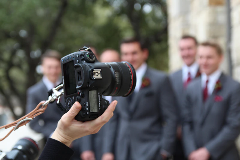 A man in a dark suit holding a camera at a wedding