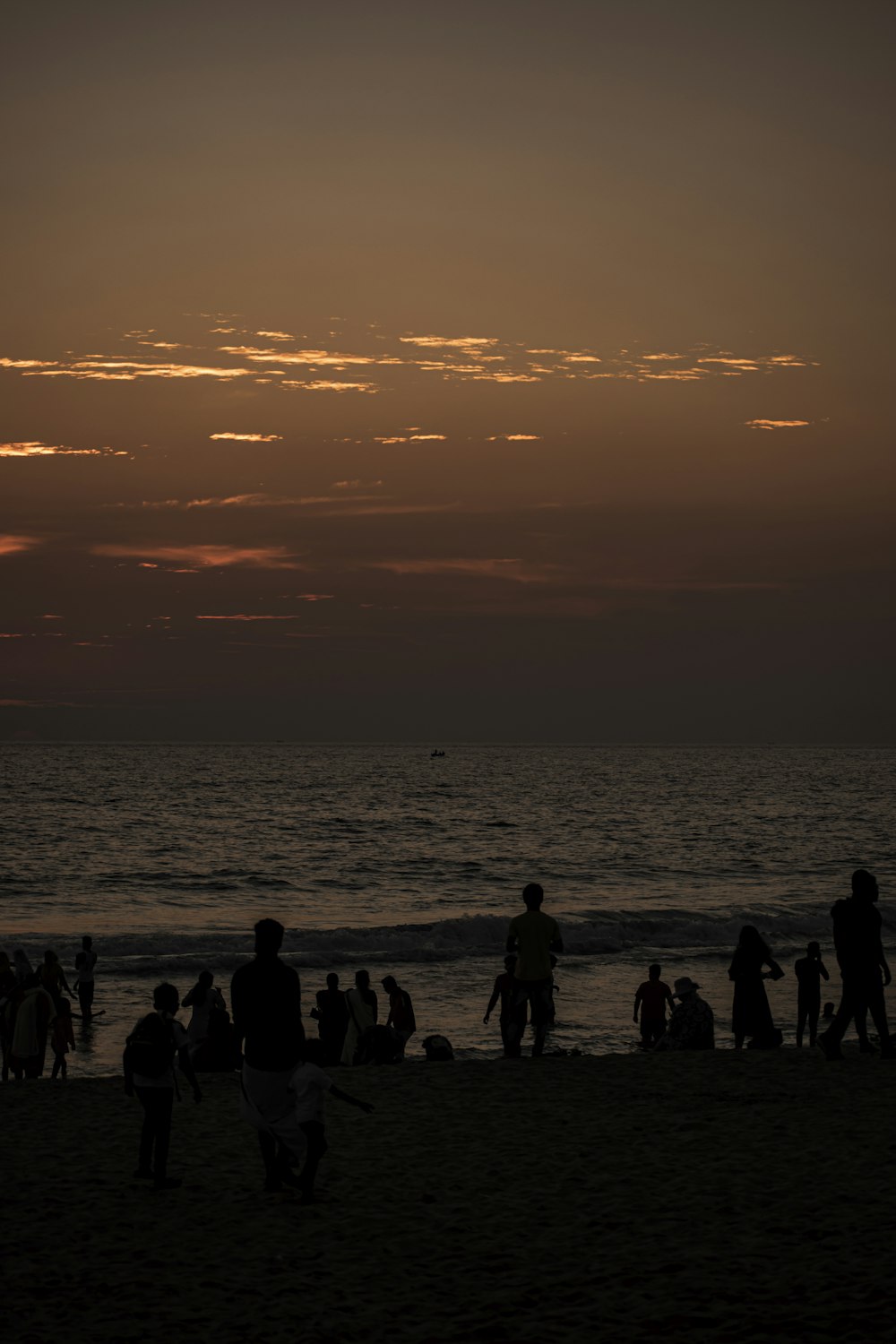 silhouette of people standing on beach during sunset