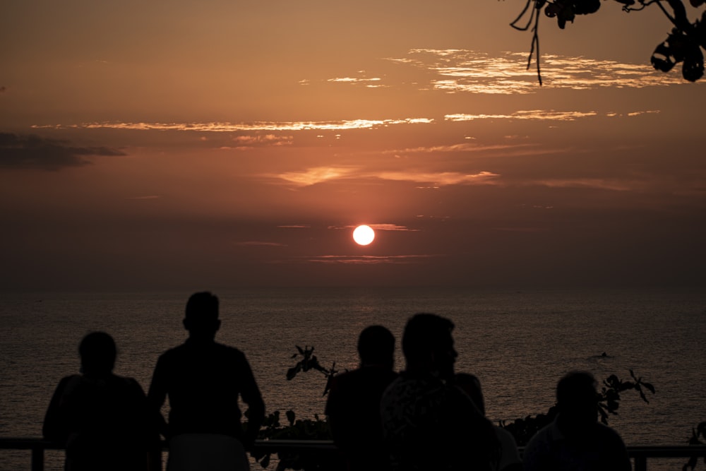 silhouette of people sitting on bench during sunset