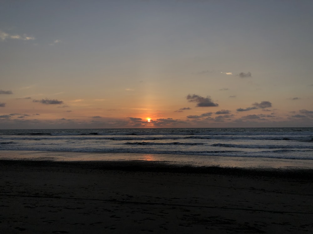 sea waves crashing on shore during sunset