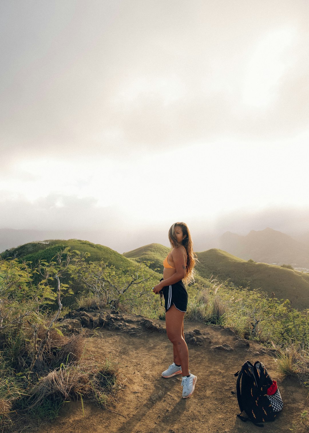 woman in black bikini standing on brown rocky mountain during daytime