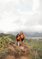 A couple smiling together on a mountain trail with lush green scenery.
