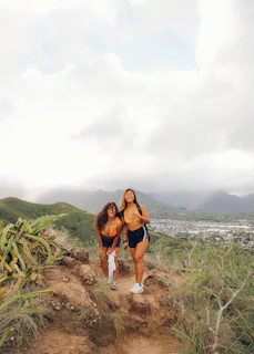 A couple smiling together on a mountain trail with lush green scenery.