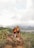 Smiling couple standing on a mountain trail with lush green Andes peaks behind them.