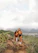 A happy couple standing on a mountain trail with lush green valleys behind them, smiling at the camera.