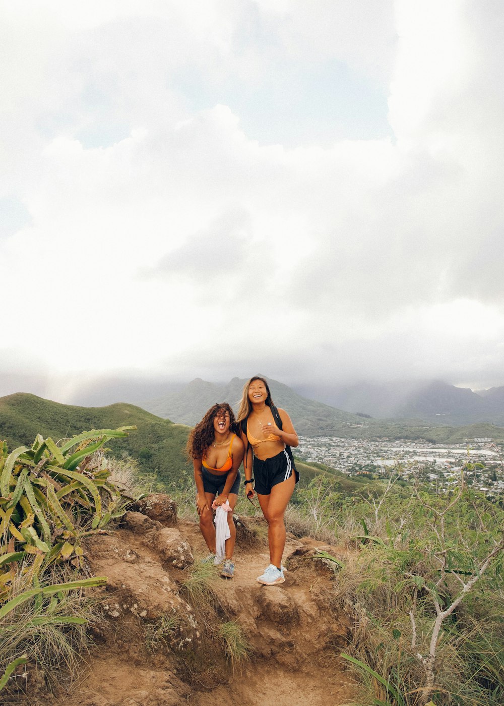 woman in black tank top and blue denim shorts standing on brown sand near green grass