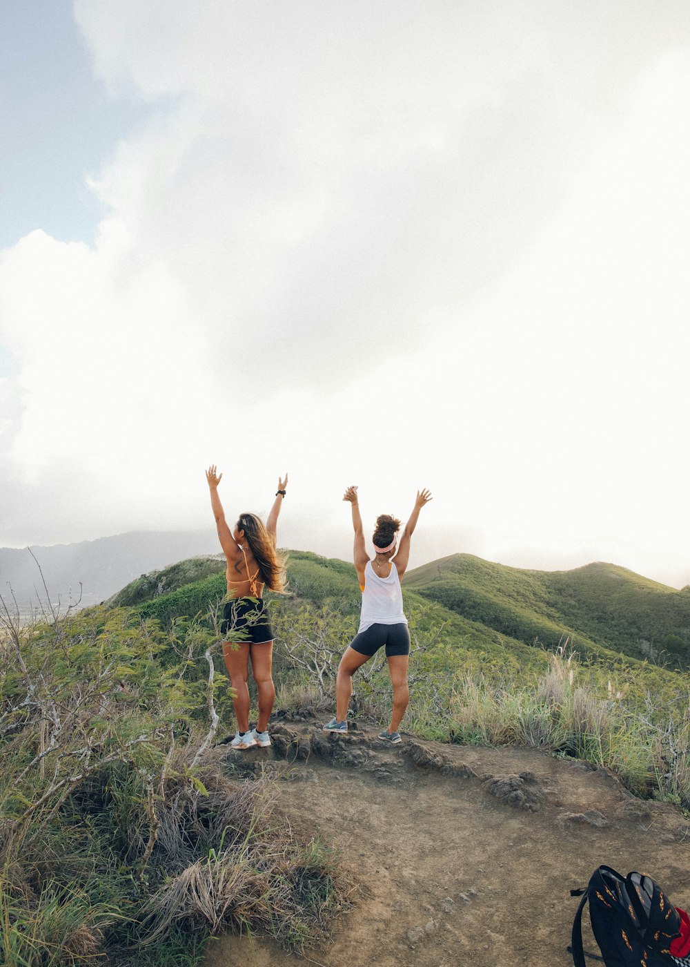 2 women in black shorts jumping on brown dirt road during daytime