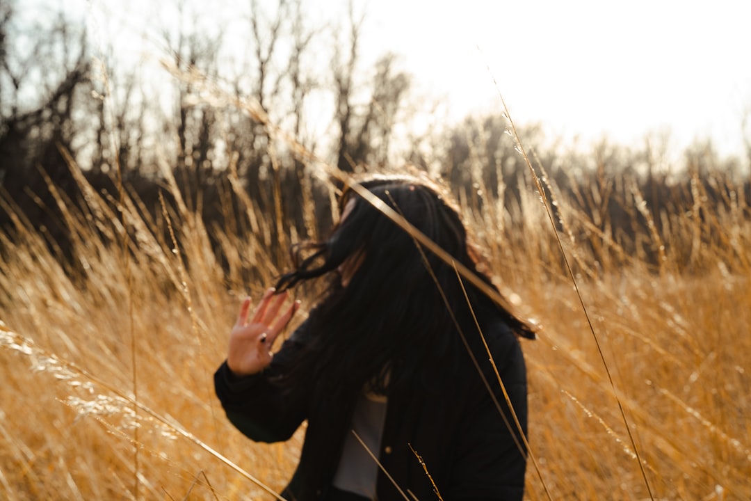 woman in black coat standing on brown grass field during daytime