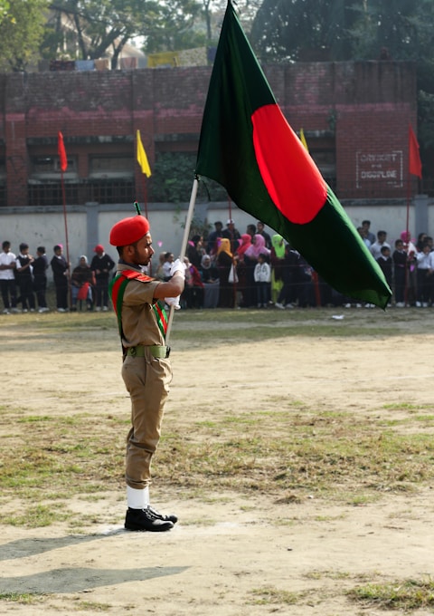 man in green uniform holding red and green flag