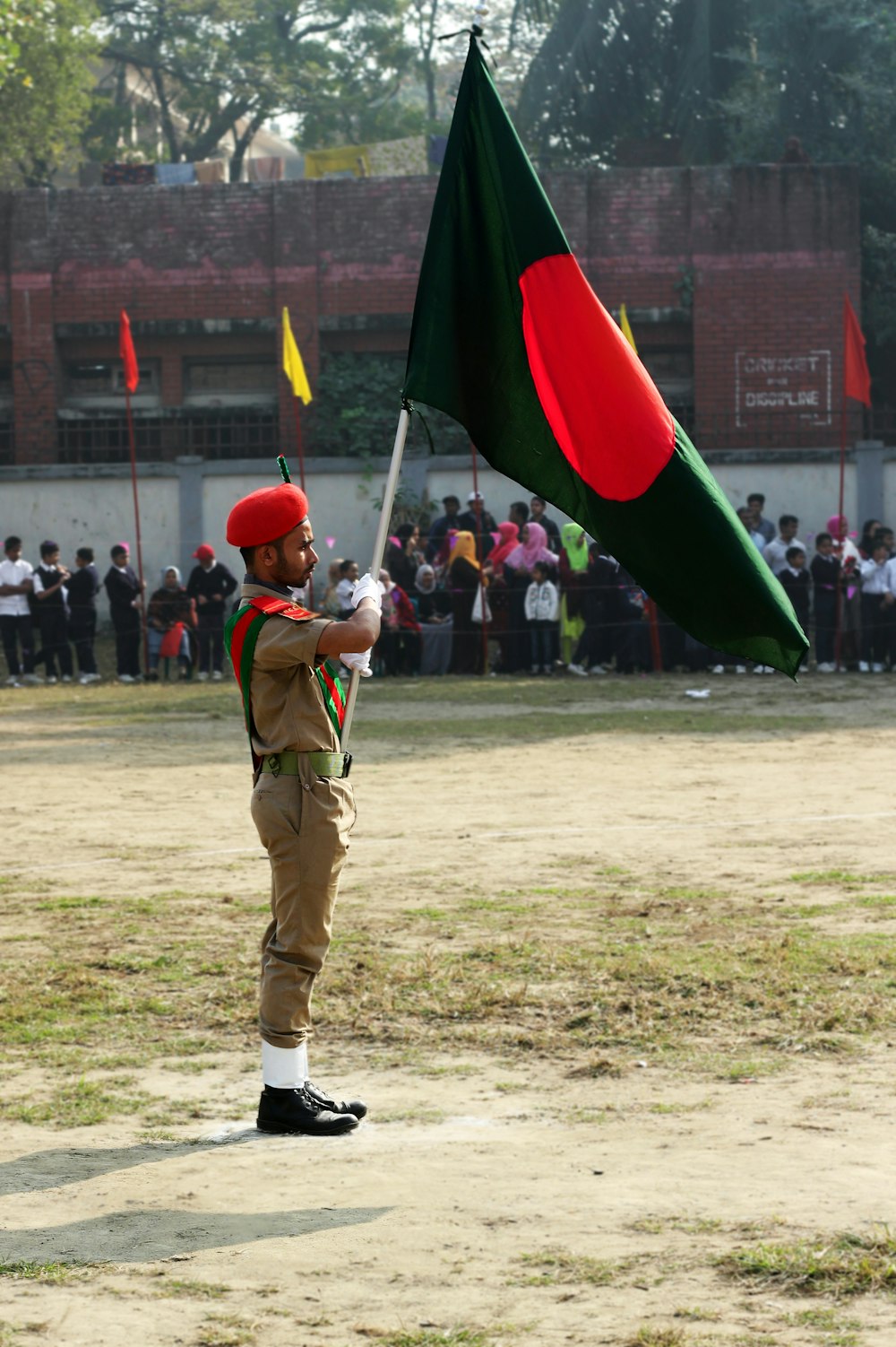 Hombre con uniforme verde sosteniendo bandera roja y verde